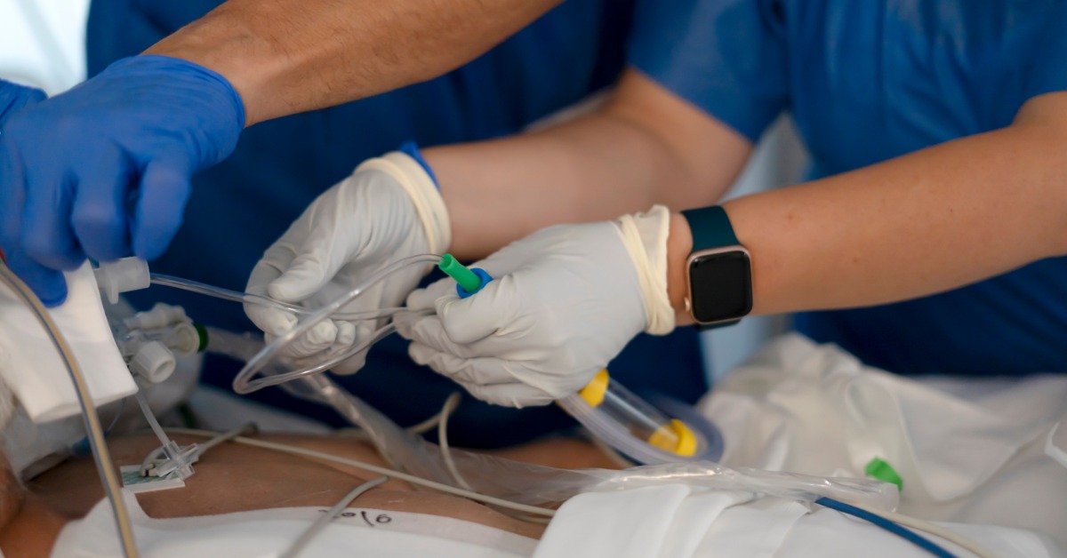 Clinicians adjusting airway tubing and ventilation equipment during procedure, demonstrating precision and teamwork in care.