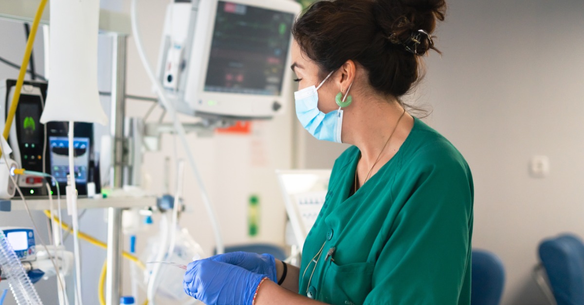 A CRNA monitors equipment and patient vitals in a clinical setting, focused on safe and controlled care delivery.